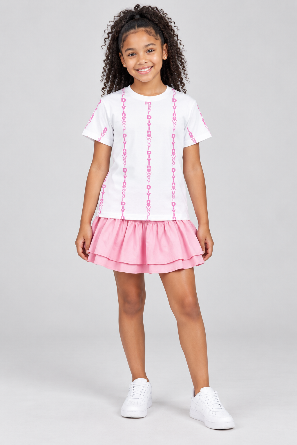 Light-skinned Jamaican youth model wearing the DivineWear Pretty in Pink unisex tee with a full pink skirt